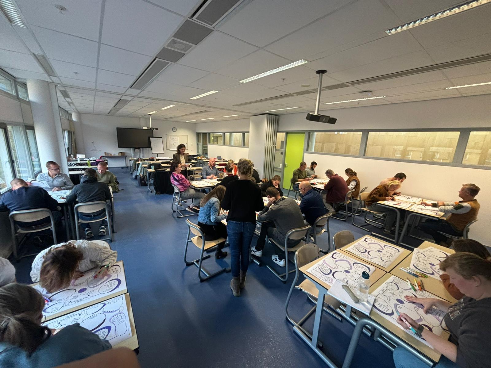 Groep deelnemers werkt aan werkbladen tijdens een workshop visueel communiceren
