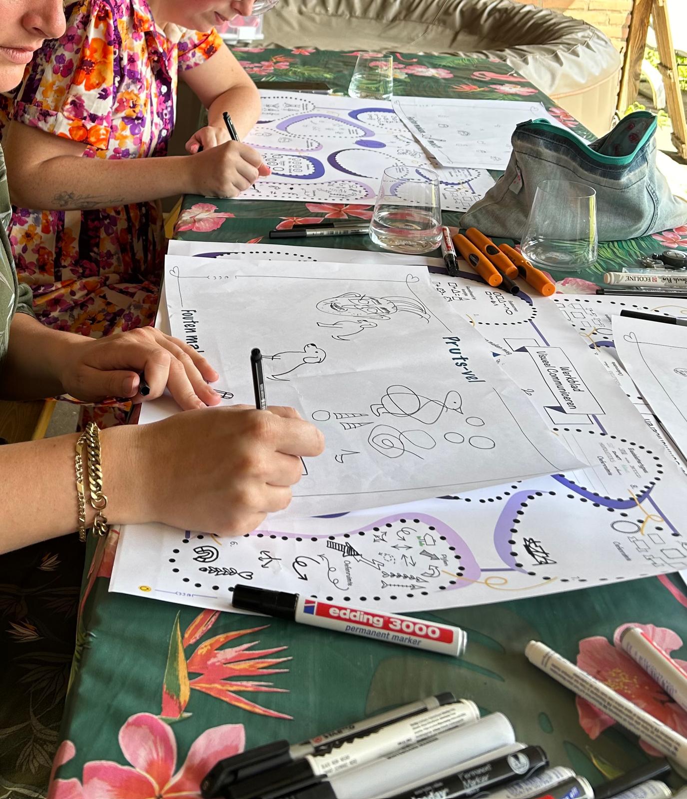 Deelnemers tekenen met markers op oefenbladen tijdens een workshop